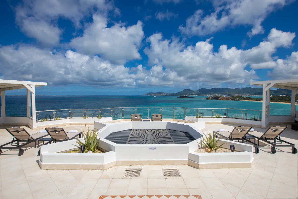 Villa Infinity Blue: Tiled sundeck terrace with lounge chairs overlooking turquoise ocean under a partly cloudy sky