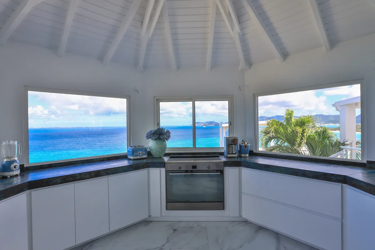 Villa Infinity Blue: Kitchen with white cabinetry and expansive panoramic windows overlooking the blue sea