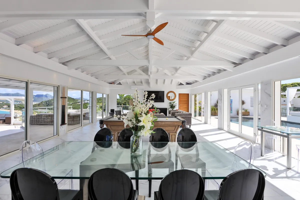 Villa Infinity Blue: Glass dining table in a bright open-concept room with vaulted ceiling and pool table