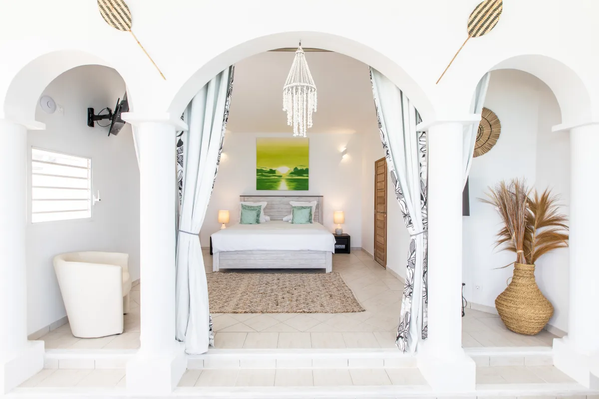 Villa Infinity Blue: Bedroom framed by white arched openings featuring a king bed and hanging chandelier