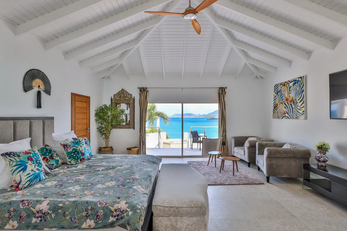 Villa Infinity Blue: Spacious bedroom with a king bed, vaulted ceiling, and sliding glass doors framing ocean views