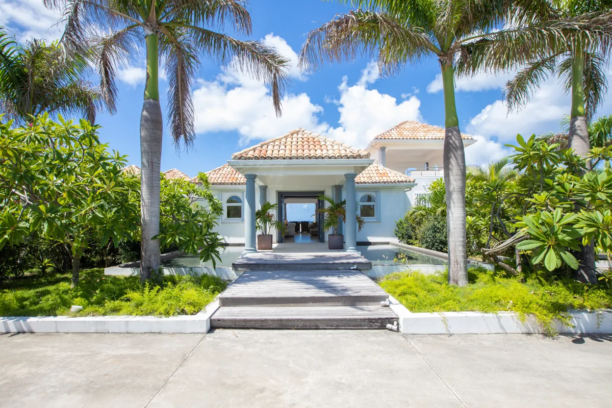 Villa Just in Paradise: Villa entrance with a wooden pathway over water framed by tall palm trees