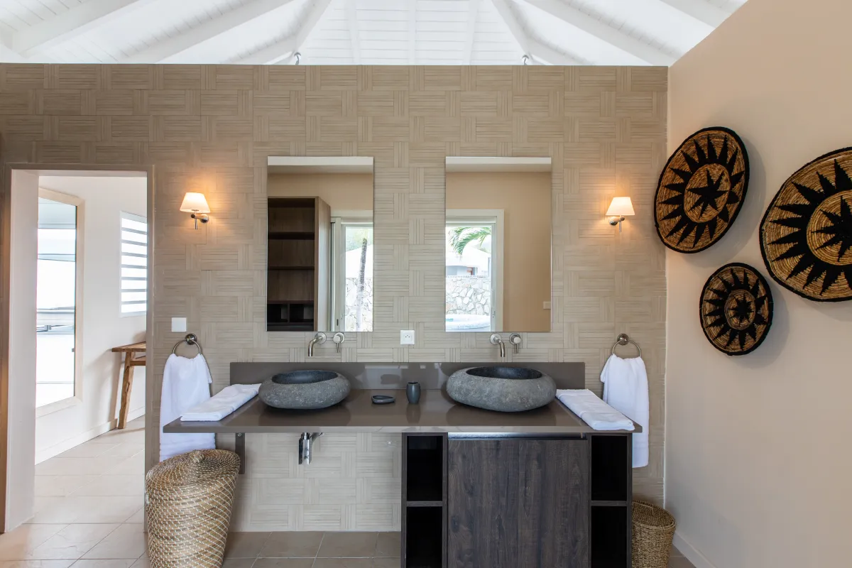 Villa Karukera: Modern bathroom featuring a double vanity with stone basin sinks and wall sconces