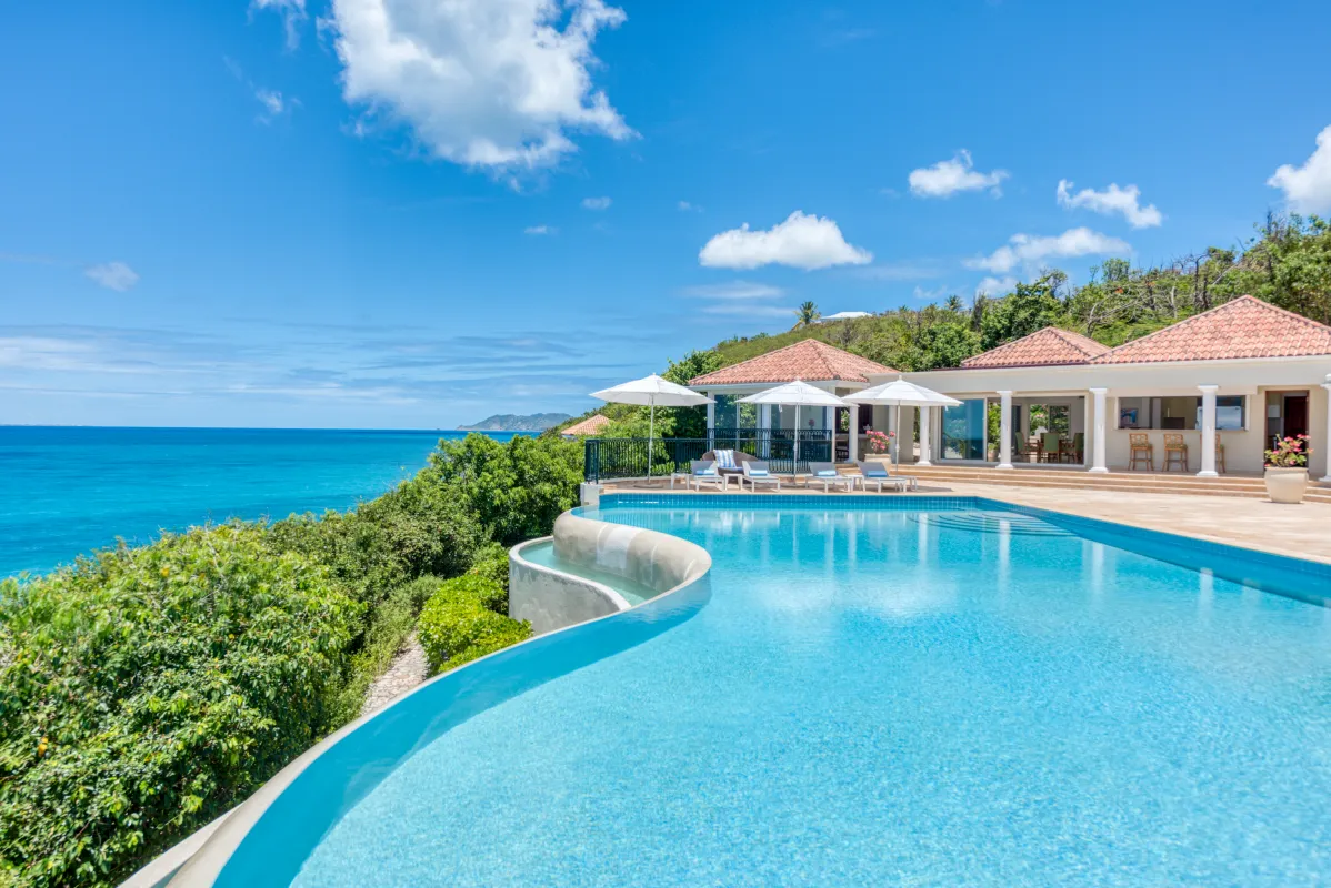 Villa La Dacha: Curved infinity swimming pool overlooking the turquoise sea under a clear blue sky