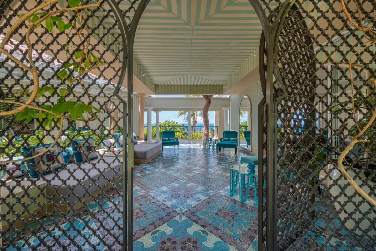 Villa La Dacha: View through decorative metal gates into a covered terrace with mosaic tile floors and seating