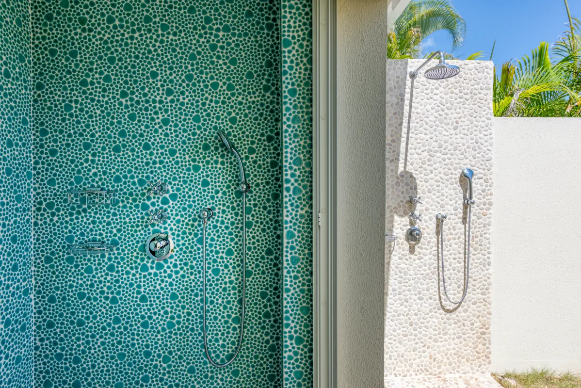 Villa La Dacha: Indoor and outdoor showers with textured pebble tile walls and chrome fixtures