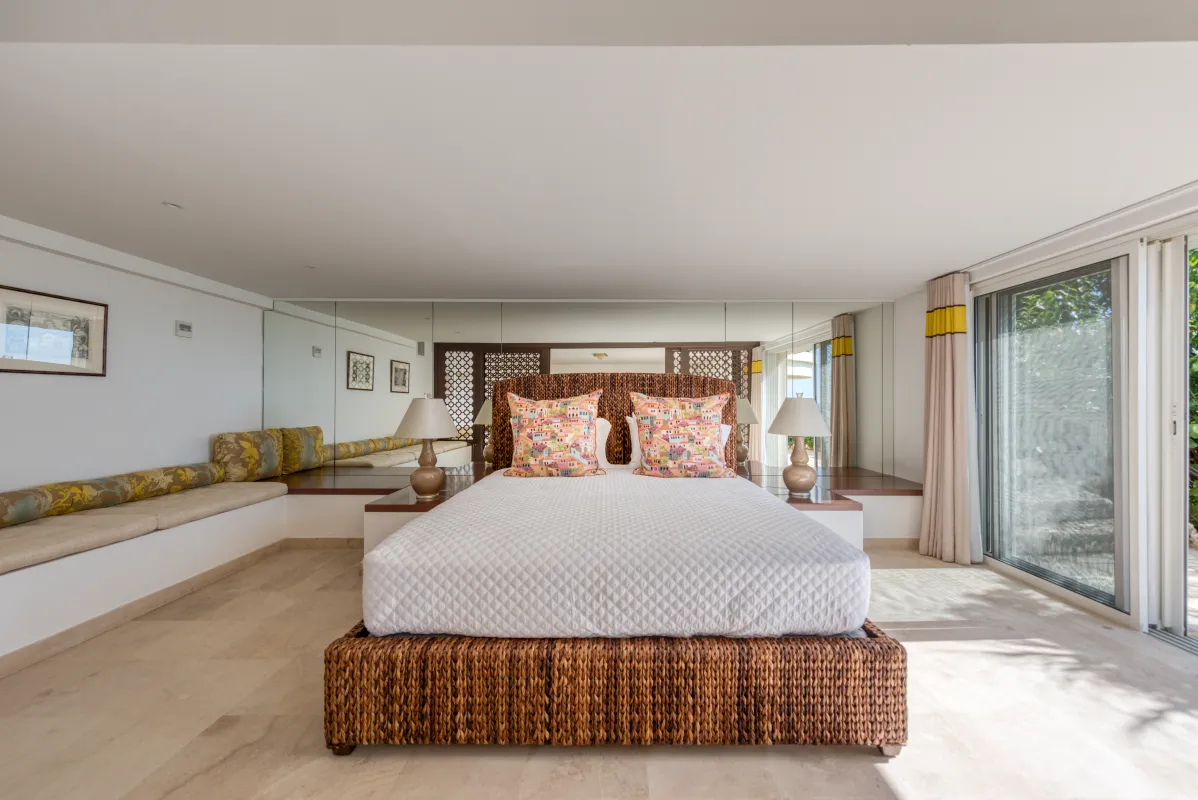 Villa La Dacha: Bedroom with a woven wicker bed, mirrored accent wall, and sliding glass doors