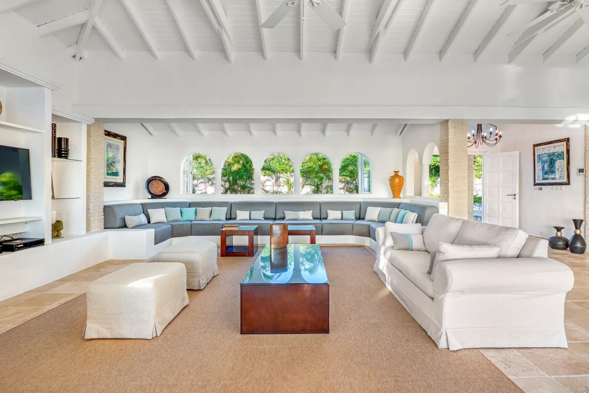 Villa La Favorita: Spacious white living room with high ceiling, large sectional sofa, and arched windows