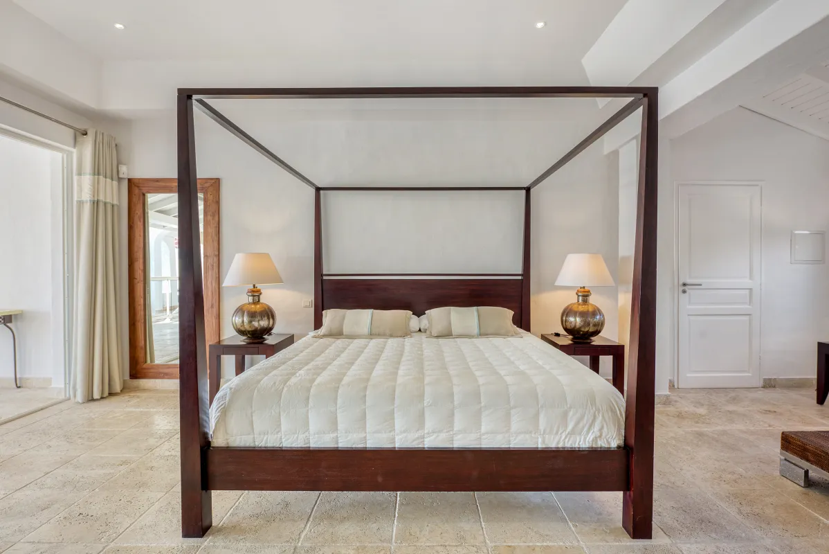 Villa La Favorita: Bedroom with a dark wood four-poster bed and bedside lamps on tiled flooring
