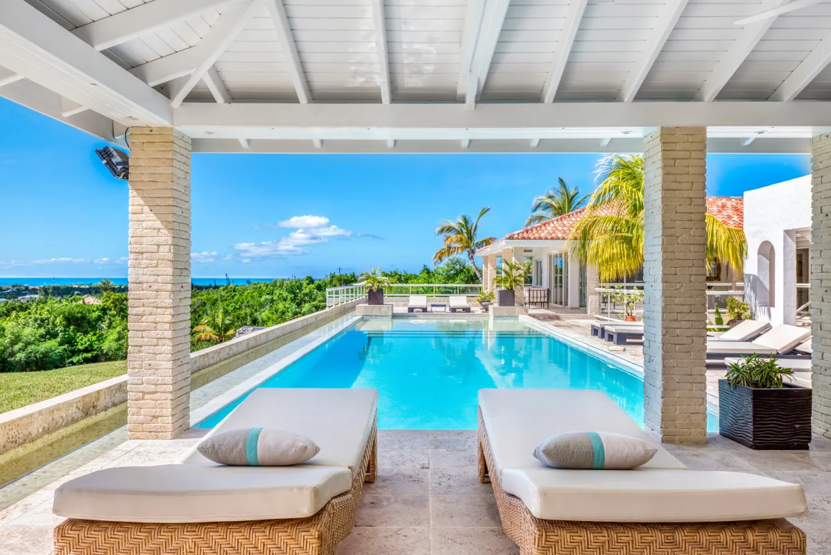 Villa La Favorita: Covered terrace with sun loungers overlooking a swimming pool and distant ocean view