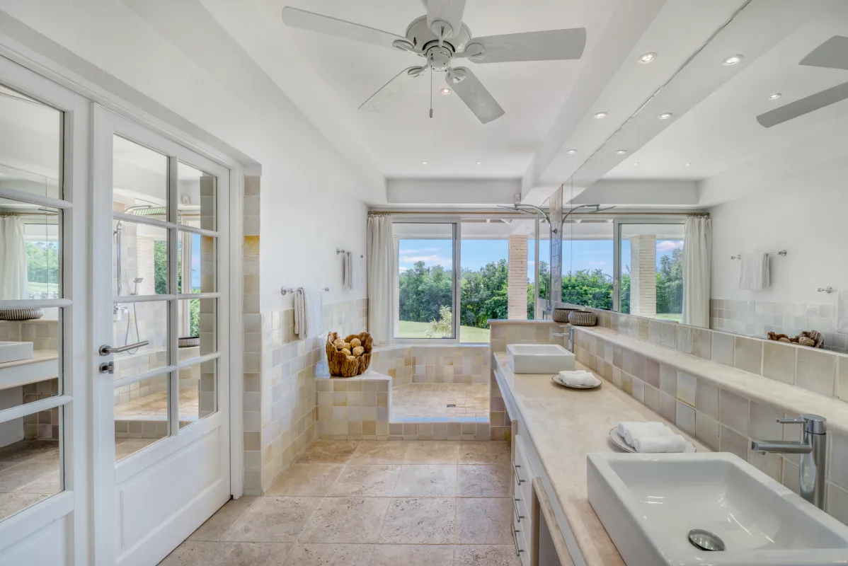 Villa La Favorita: Spacious bathroom with double vanity, ceiling fan, and sunken shower area overlooking trees