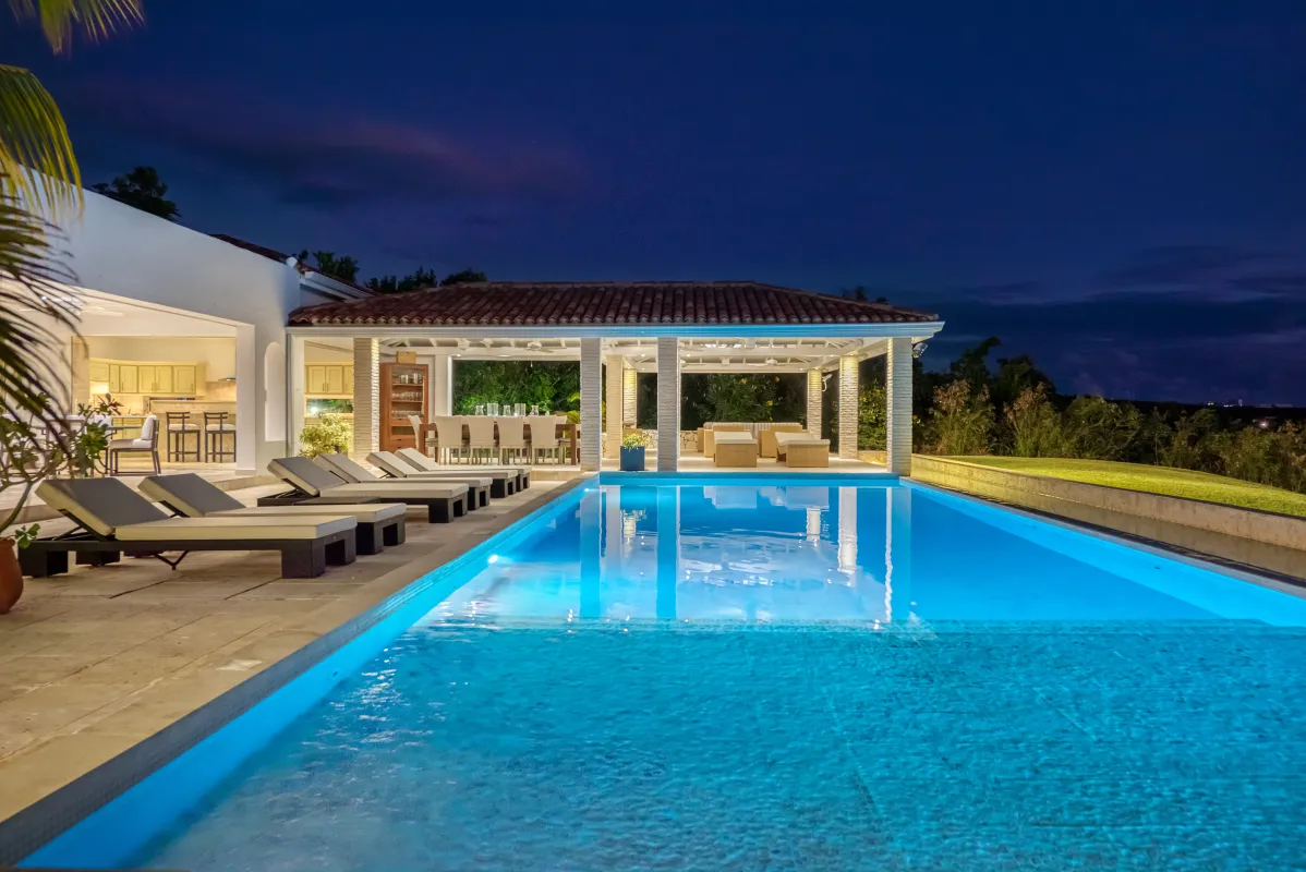 Villa La Favorita: Illuminated swimming pool and covered terrace with sun loungers at dusk