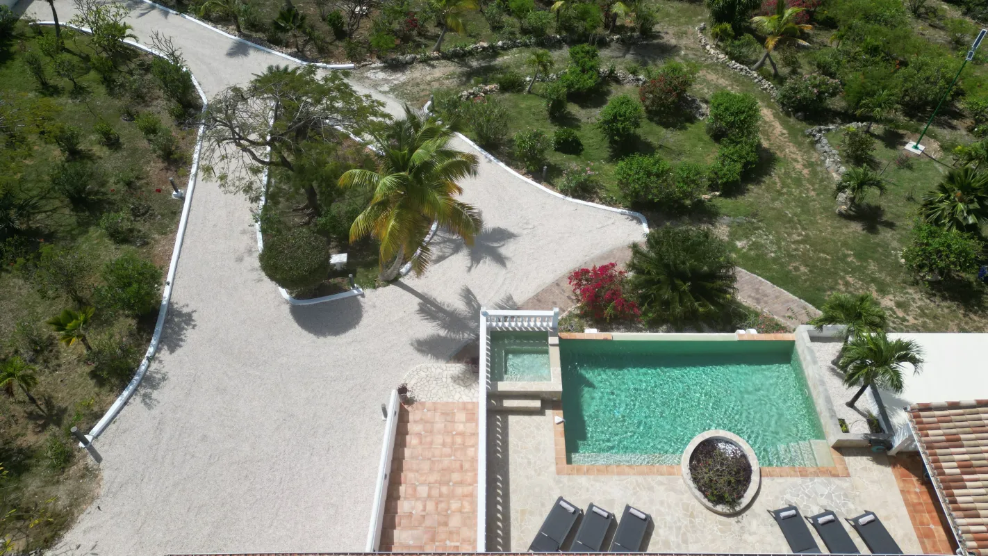 Villa La Rose Du Desert: Aerial view of a swimming pool, sun loungers, driveway, and lush landscaped garden