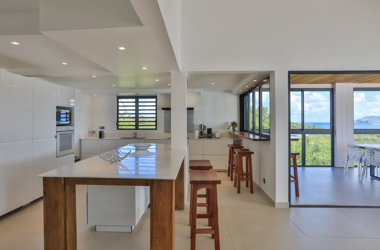 Villa La Siesta: Modern white kitchen with island wooden bar stools and view of the sea