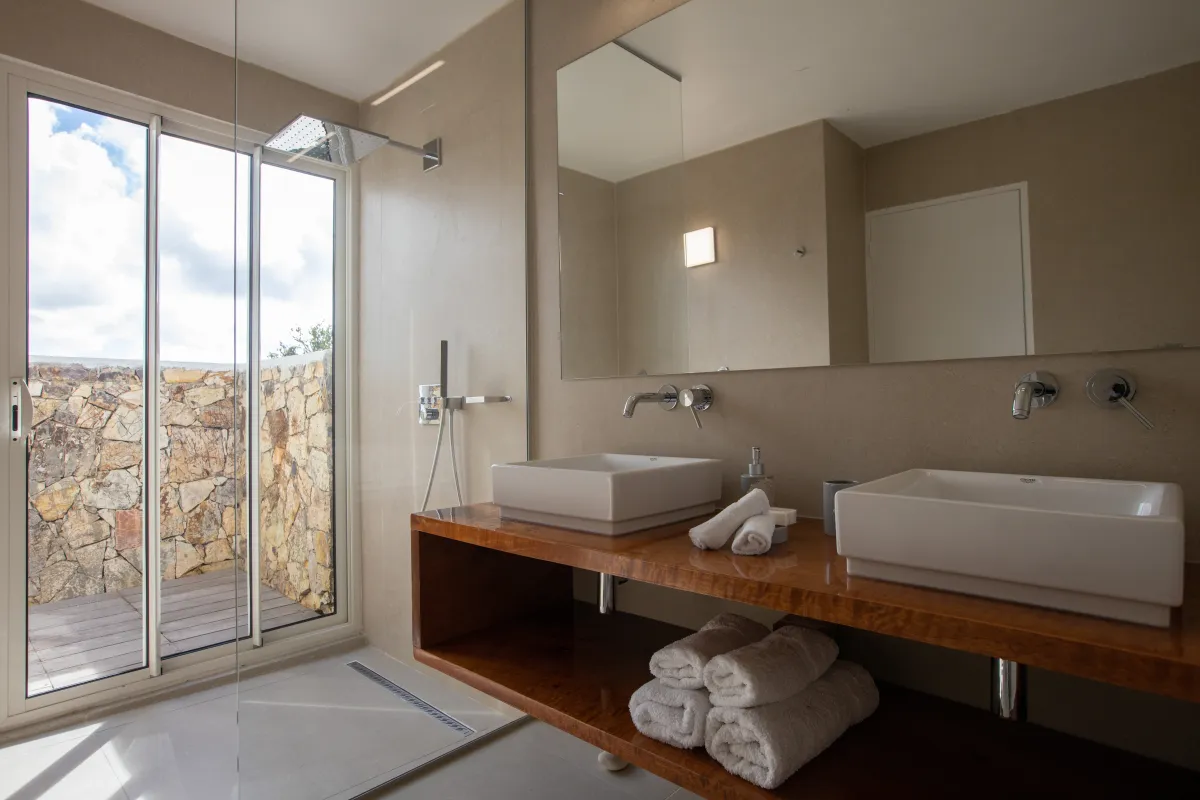 Villa La Siesta: Bathroom with double sinks, wooden vanity, and walk-in shower opening to an outdoor patio