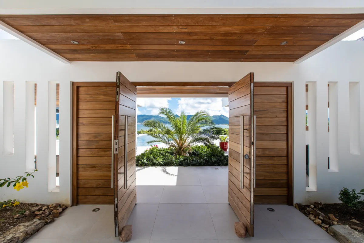 Villa La Siesta: Open wooden double doors at the villa entrance framing a palm tree and sea view