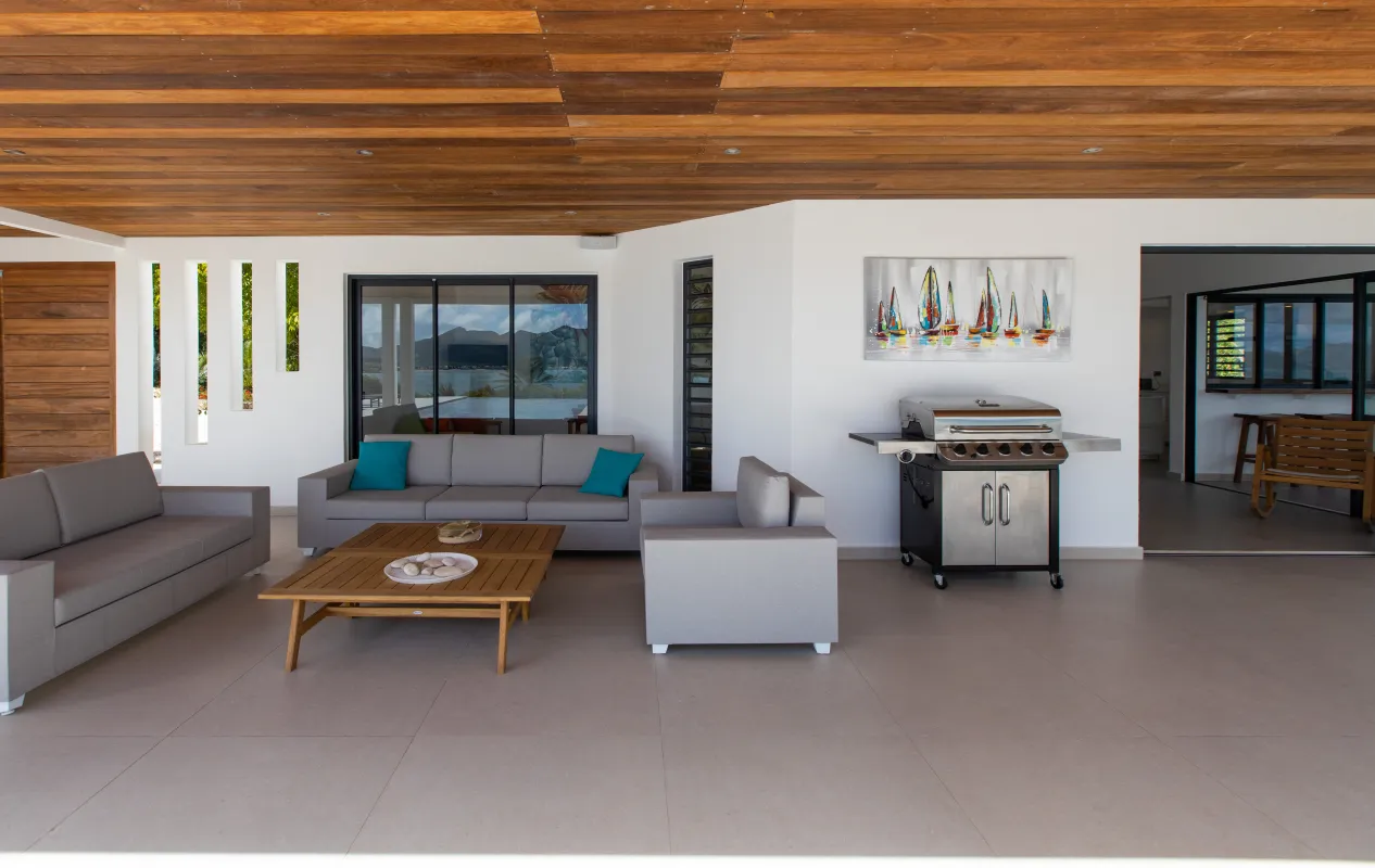 Villa La Siesta: Covered terrace with grey lounge seating, wooden coffee table, and stainless steel barbecue grill