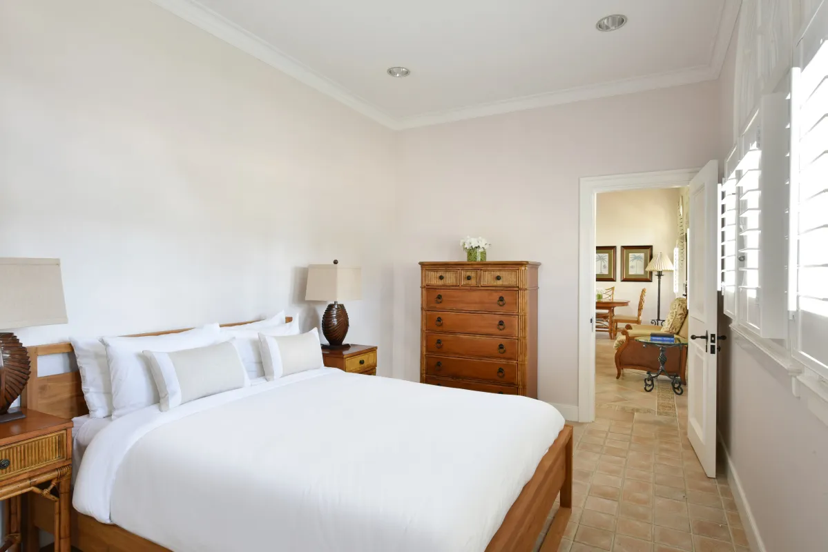 Villa Le Chateau Des Palmiers: Bedroom with a wooden bed, white linens, tall dresser, and doorway into the living area