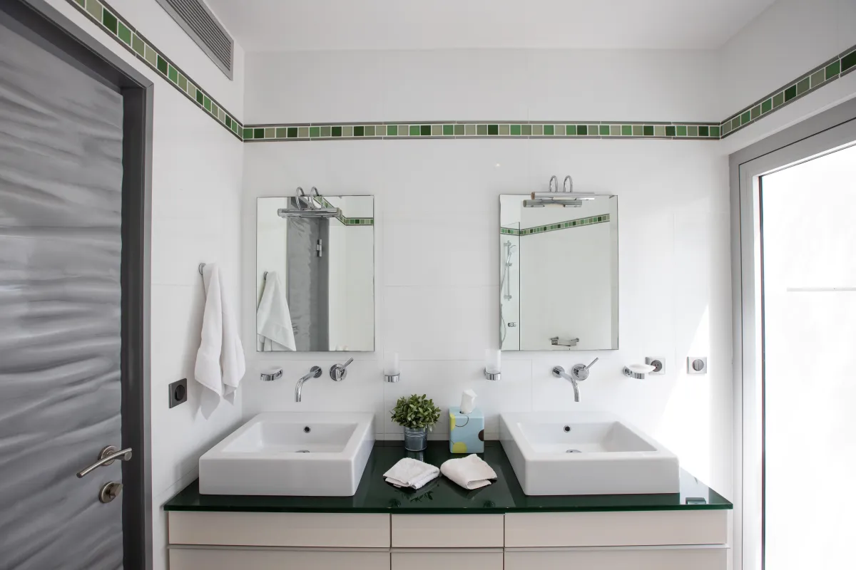 Villa Le Rêve: Bathroom vanity with two vessel sinks, dual mirrors, and green accent tile