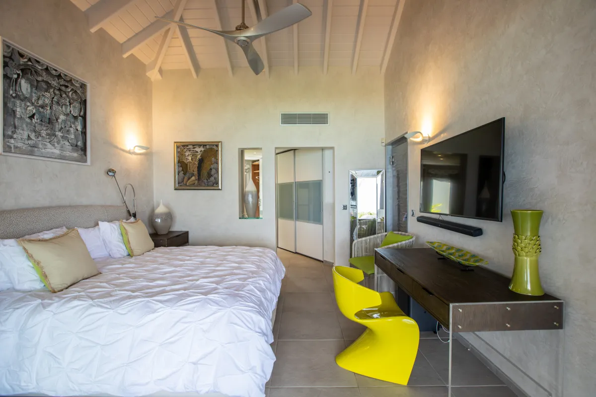 Villa Le Rêve: Modern bedroom with a king bed, yellow accent chair, wall-mounted television, and high ceiling