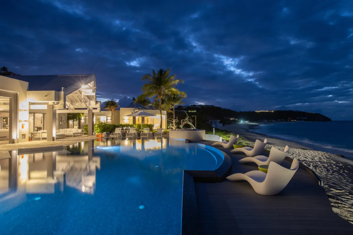 Villa Le Rêve: Illuminated swimming pool and deck with modern loungers overlooking the beach at dusk