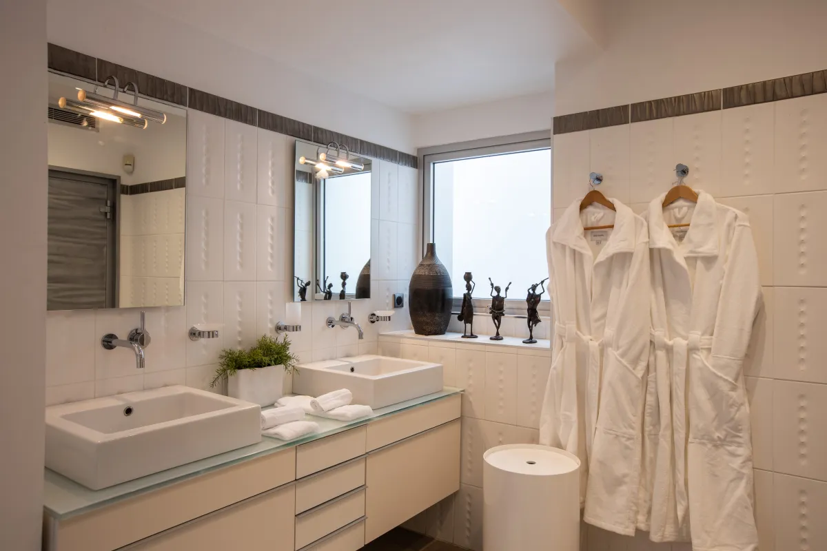 Villa Le Rêve: Bathroom with double vanity sinks, wall mirrors, and hanging white bathrobes