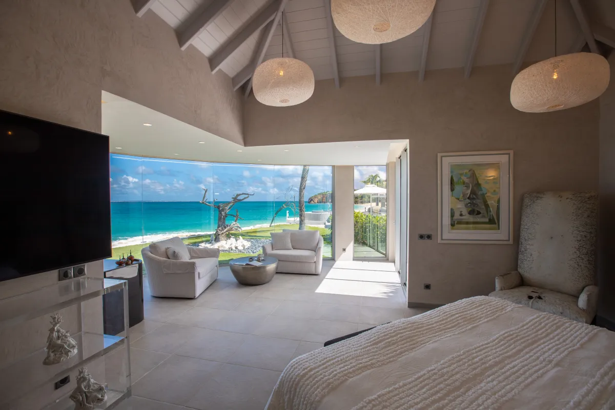 Villa Le Rêve: Spacious bedroom with ocean view through panoramic glass windows and a seating area