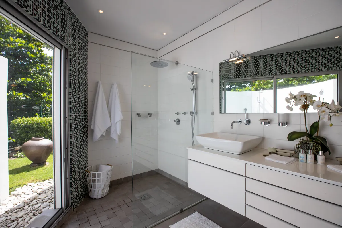 Villa Le Rêve: Modern bathroom with a glass walk-in shower vanity and sliding door opening to the garden