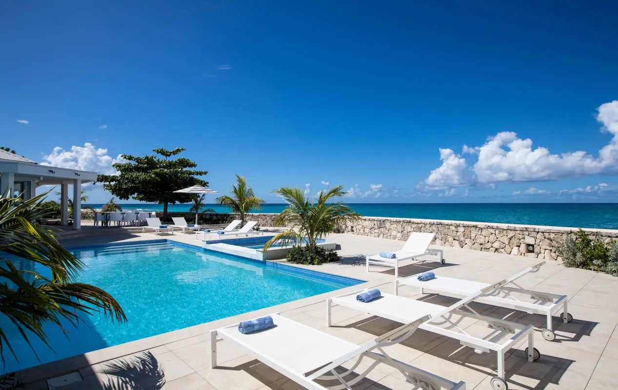 Villa L'Ecume des Jours: Swimming pool and sun terrace with loungers overlooking the ocean under a clear blue sky
