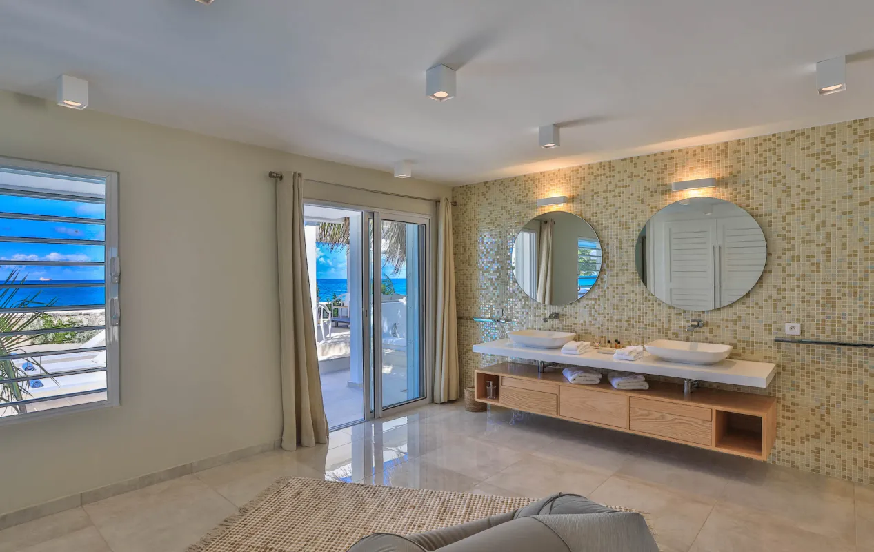 Villa L'Ecume des Jours: Modern bathroom with double vanity, circular mirrors, and sliding glass doors to a terrace