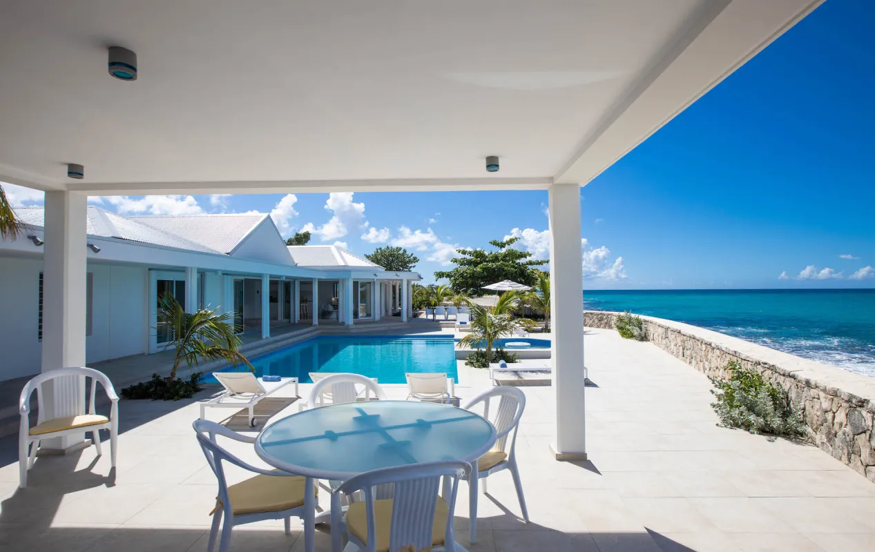Villa L'Ecume des Jours: Covered terrace with an outdoor dining table overlooking a swimming pool and the ocean