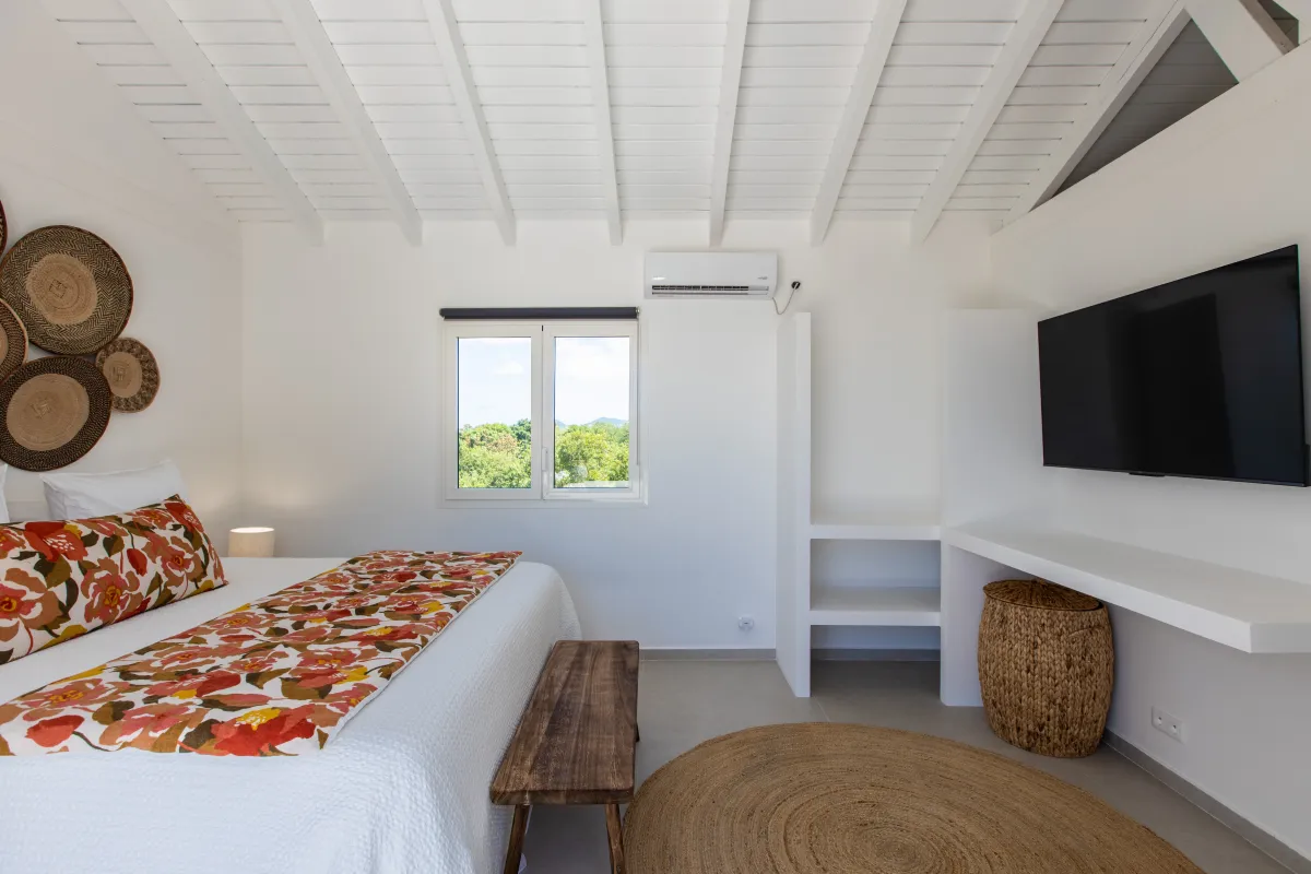 Villa Les Oliviers: Bedroom with vaulted white wood ceiling, wall-mounted television, and floral bed runner
