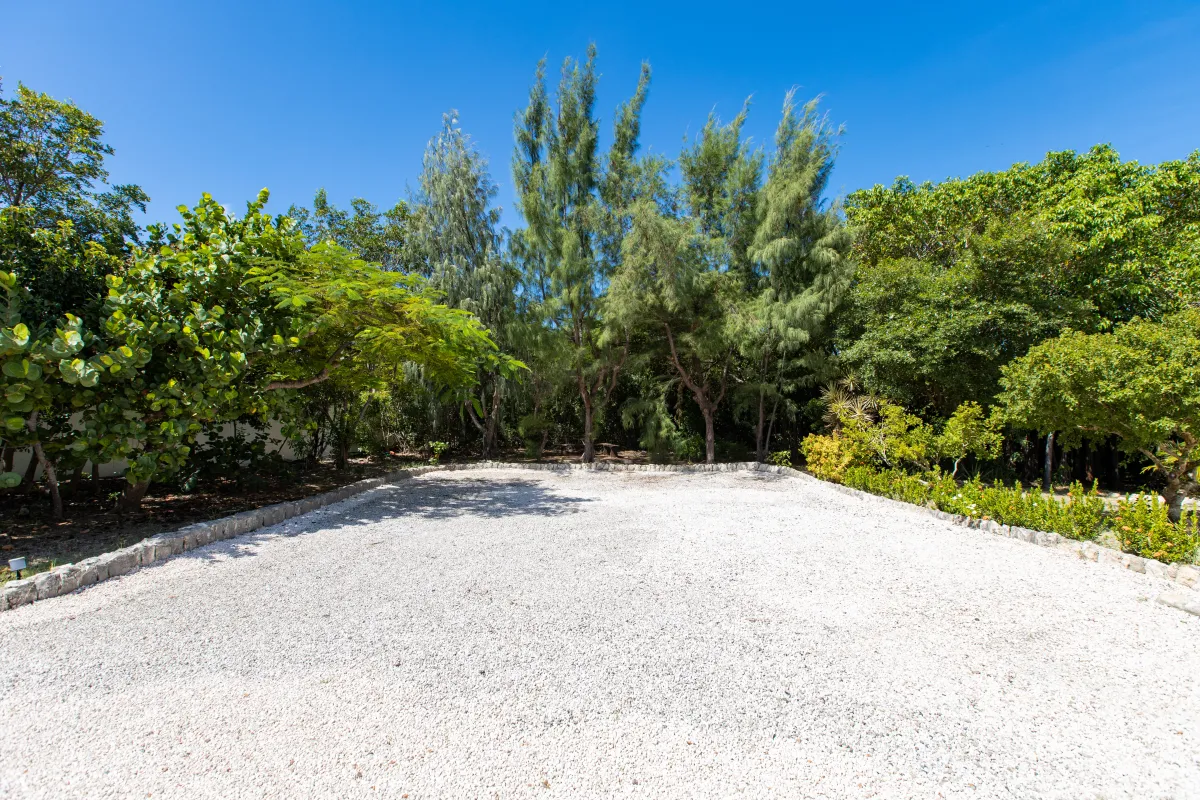Villa Les Oliviers: Gravel driveway and parking area bordered by stone curbs and lush tropical trees