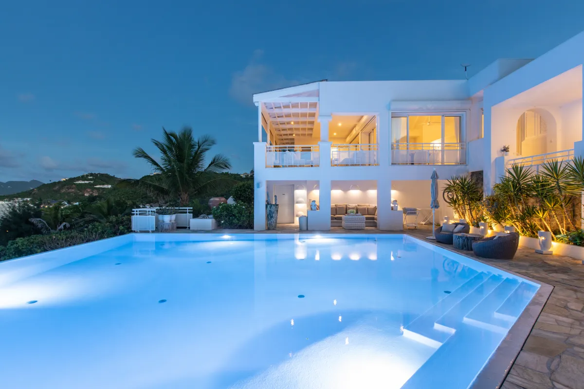 Villa L'Oasis: Illuminated swimming pool and patio outside a modern white villa at dusk