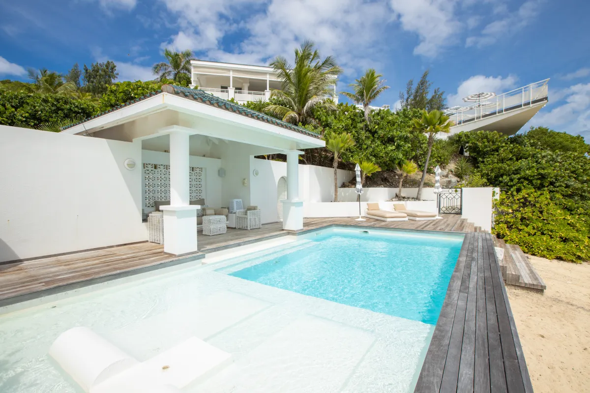 Villa L'Oasis: Swimming pool with submerged lounger, wooden deck, and covered pavilion by tropical hillside