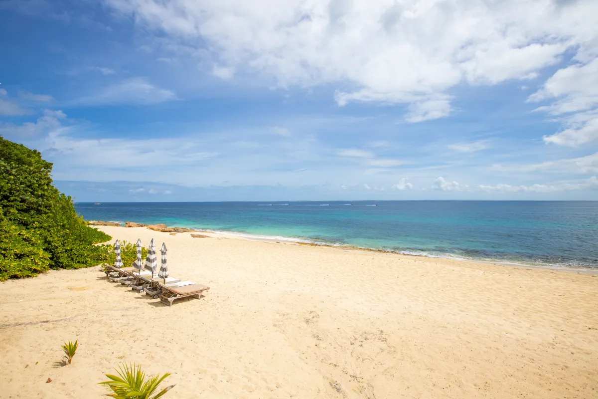 Villa L'Oasis: Sandy beach with sun loungers and umbrellas overlooking clear turquoise water
