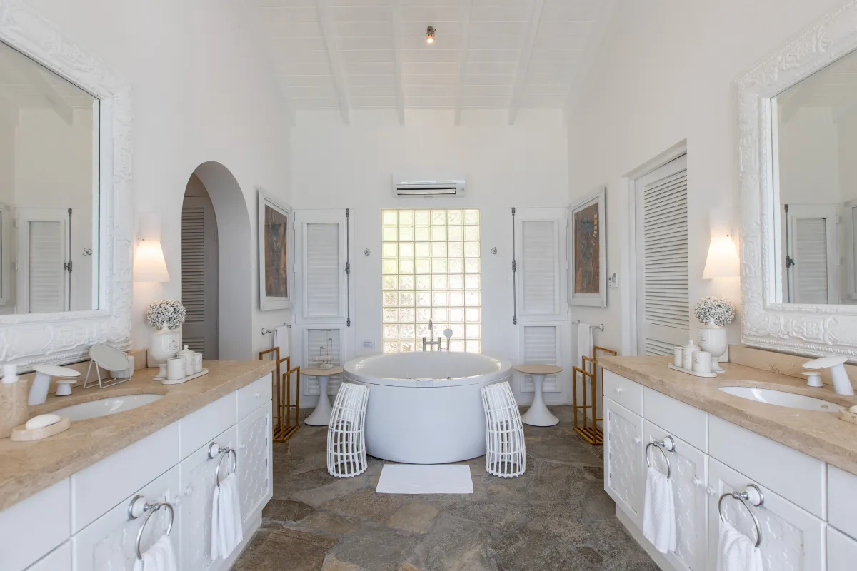 Villa L'Oasis: Spacious bathroom featuring two vanities, stone tile floor, and a round freestanding soaking tub