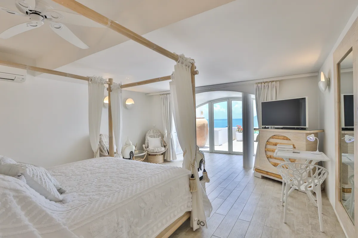 Villa L'Oasis: Bedroom with a four-poster canopy bed, television, and doors opening to sea views