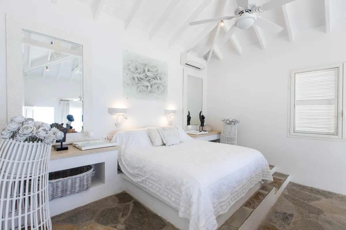 Villa L'Oasis: Bedroom with white bed, stone flooring, vaulted ceiling, and built-in bedside vanities