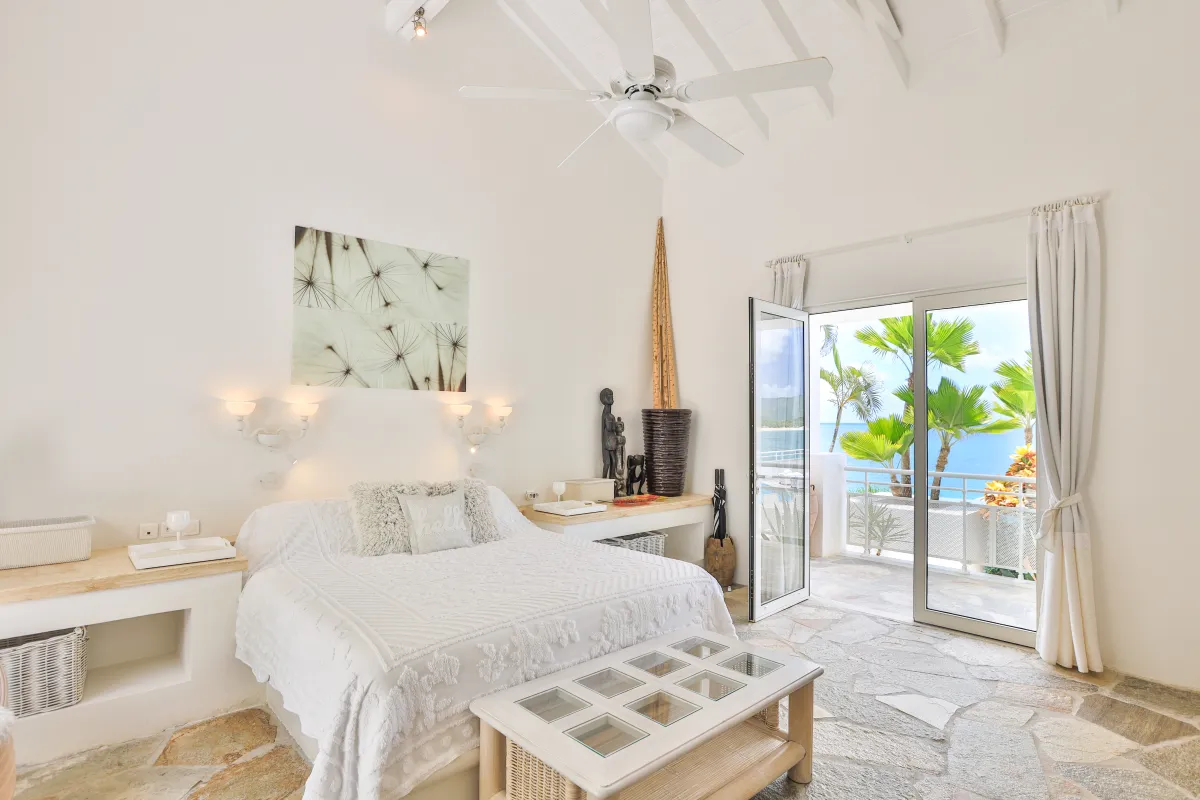 Villa L'Oasis: Bright bedroom with a king bed and glass doors opening to a sea-view terrace