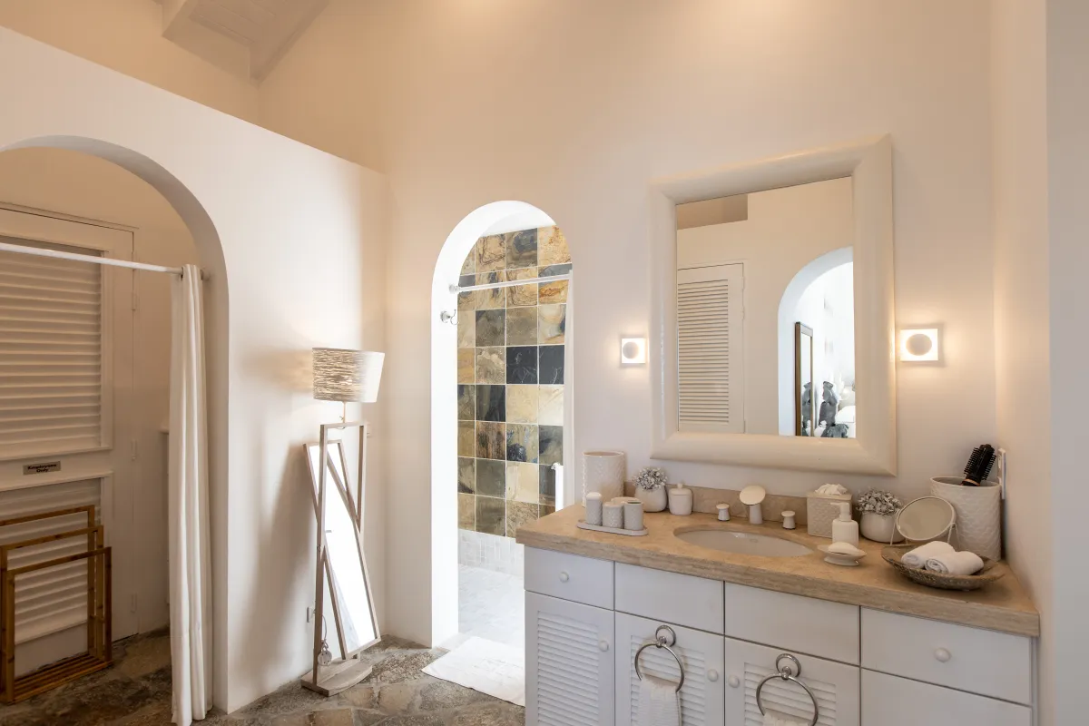 Villa L'Oasis: Bathroom vanity with mirror and arched entryway leading to tiled shower area