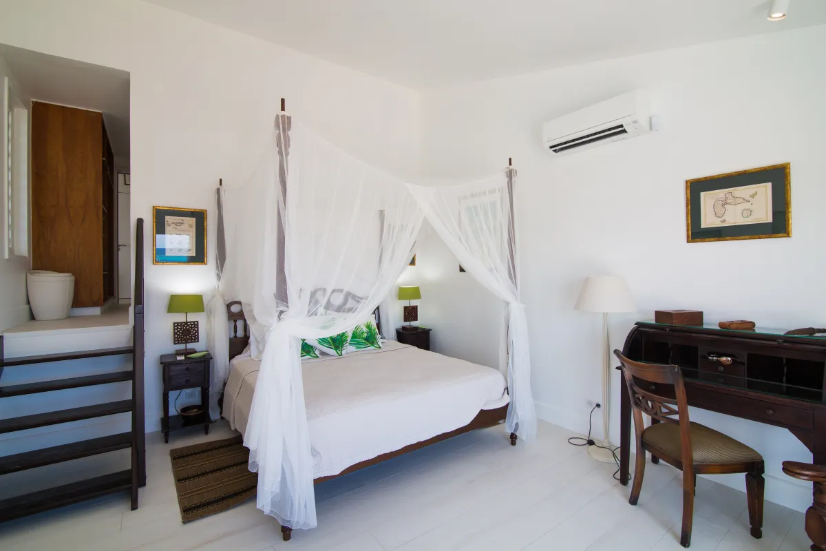 Villa Mango: Bedroom with a four-poster canopy bed draped in white netting and a wooden writing desk