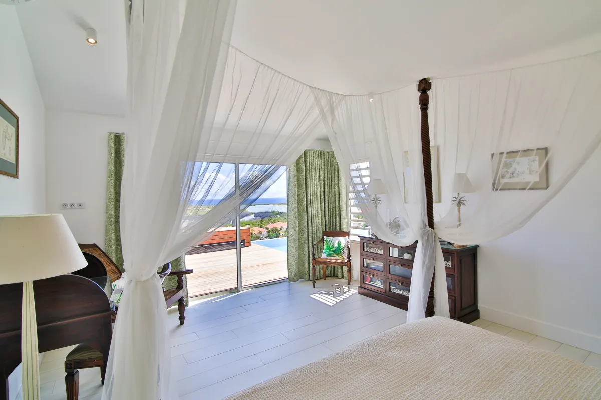 Villa Mango: Bedroom with a draped canopy bed and sliding glass doors opening to a terrace