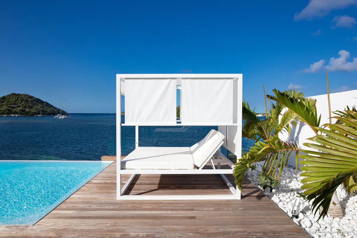 Villa Mapai: White cabana daybed on a wooden deck next to a pool overlooking the sea