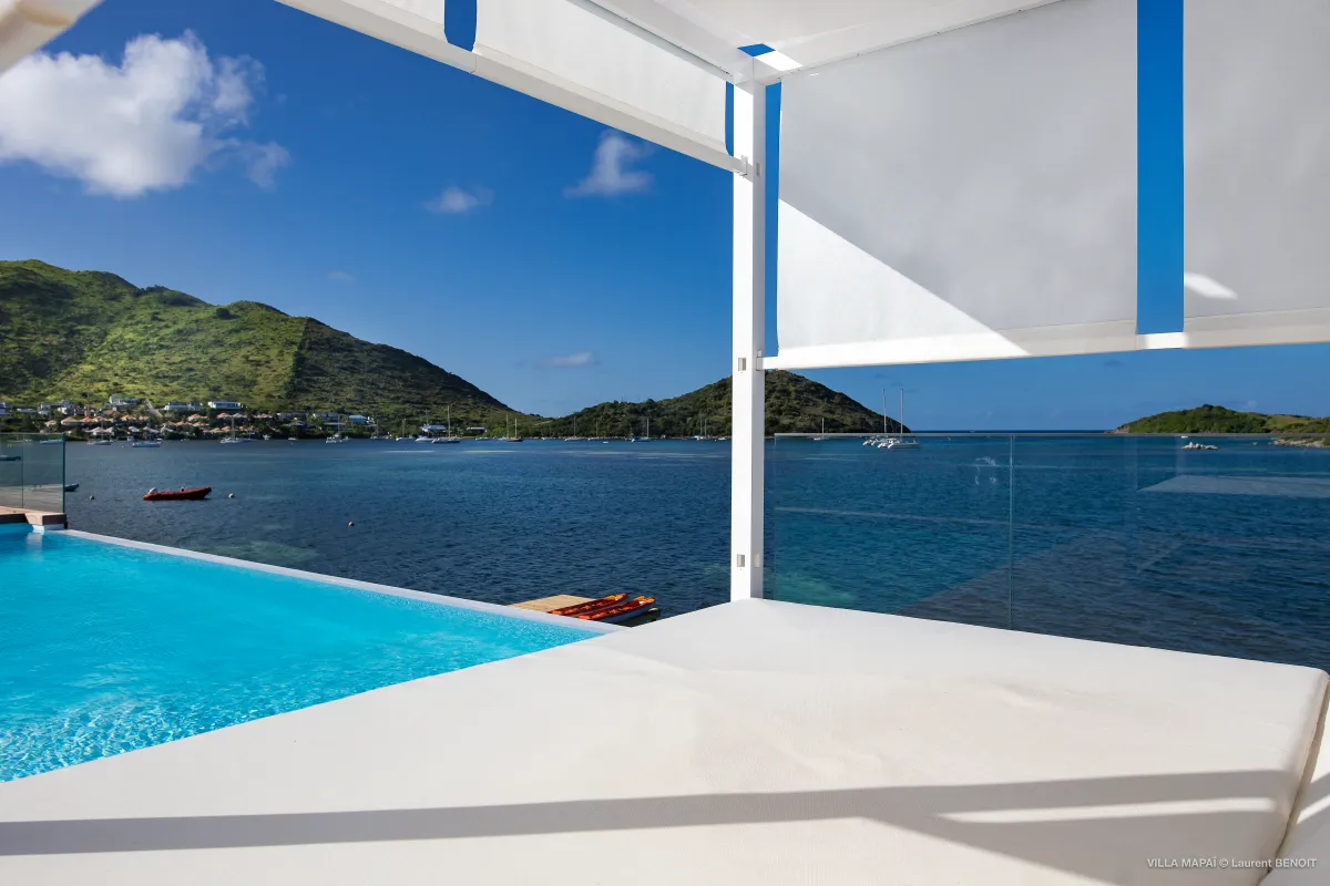 Villa Mapai: Shaded daybed beside an infinity pool overlooking a calm bay and hills