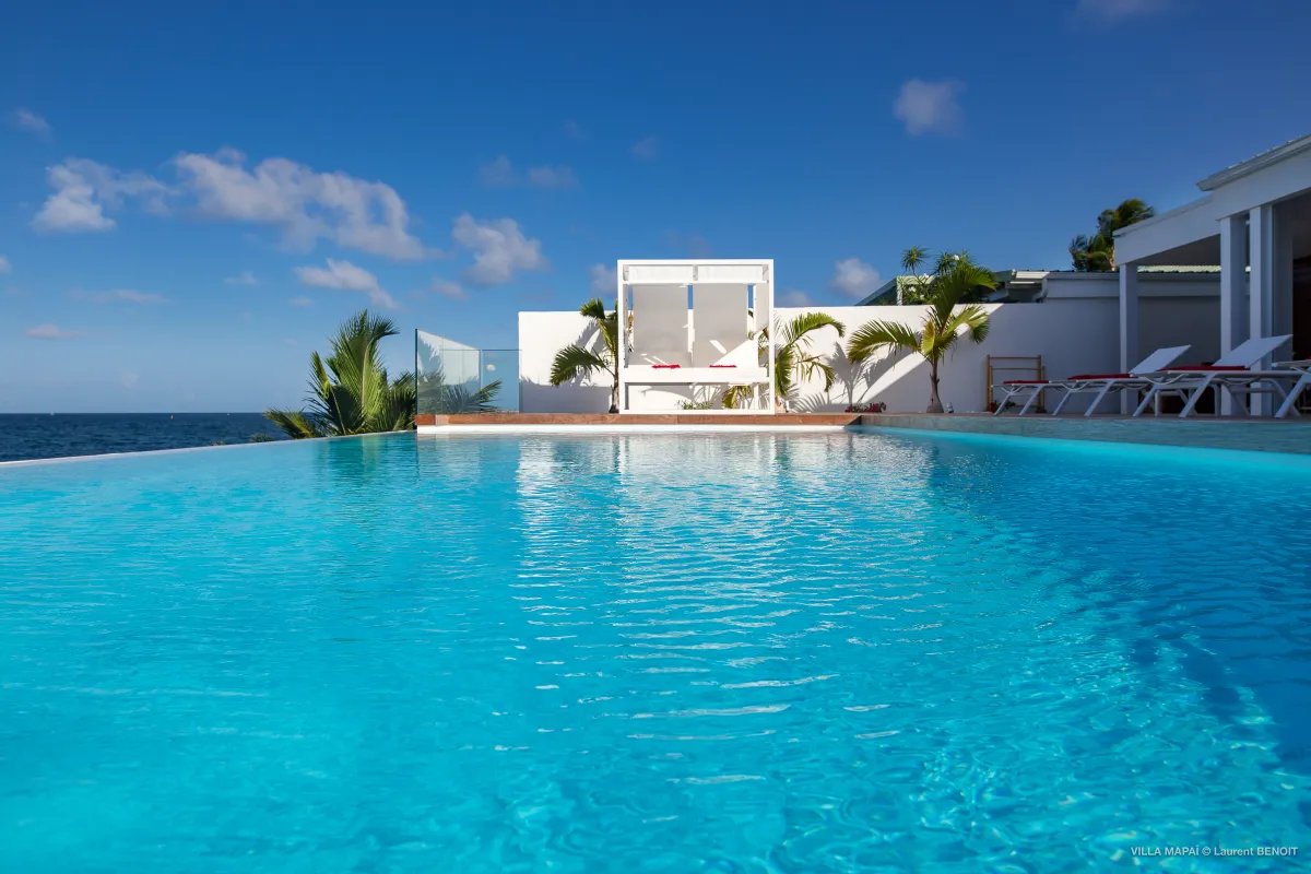 Villa Mapai: Infinity swimming pool overlooking the ocean with a shaded daybed and sun loungers