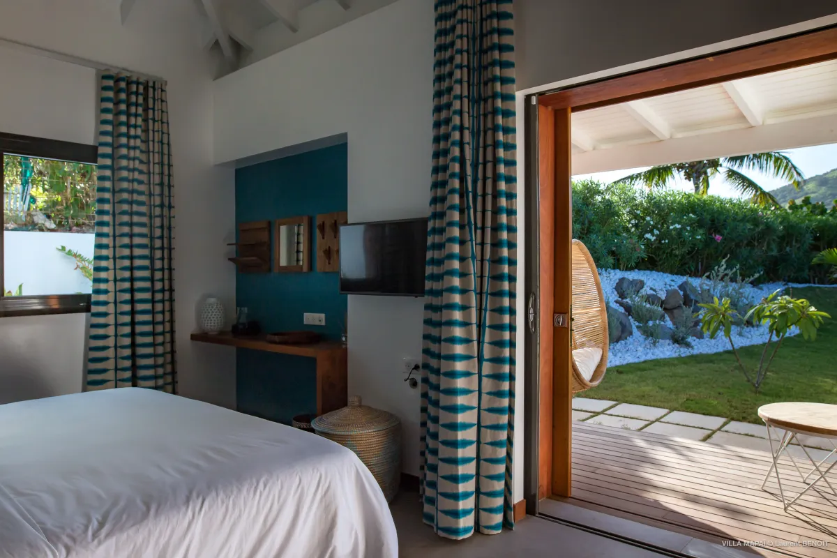 Villa Mapai: Bedroom with patterned curtains and sliding door opening to a garden patio