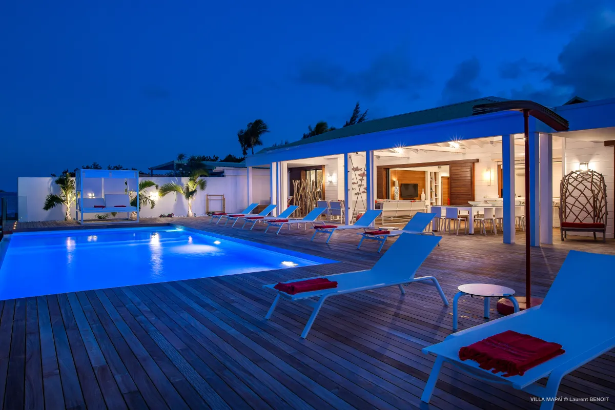 Villa Mapai: Illuminated swimming pool and sun loungers on a wooden terrace at dusk