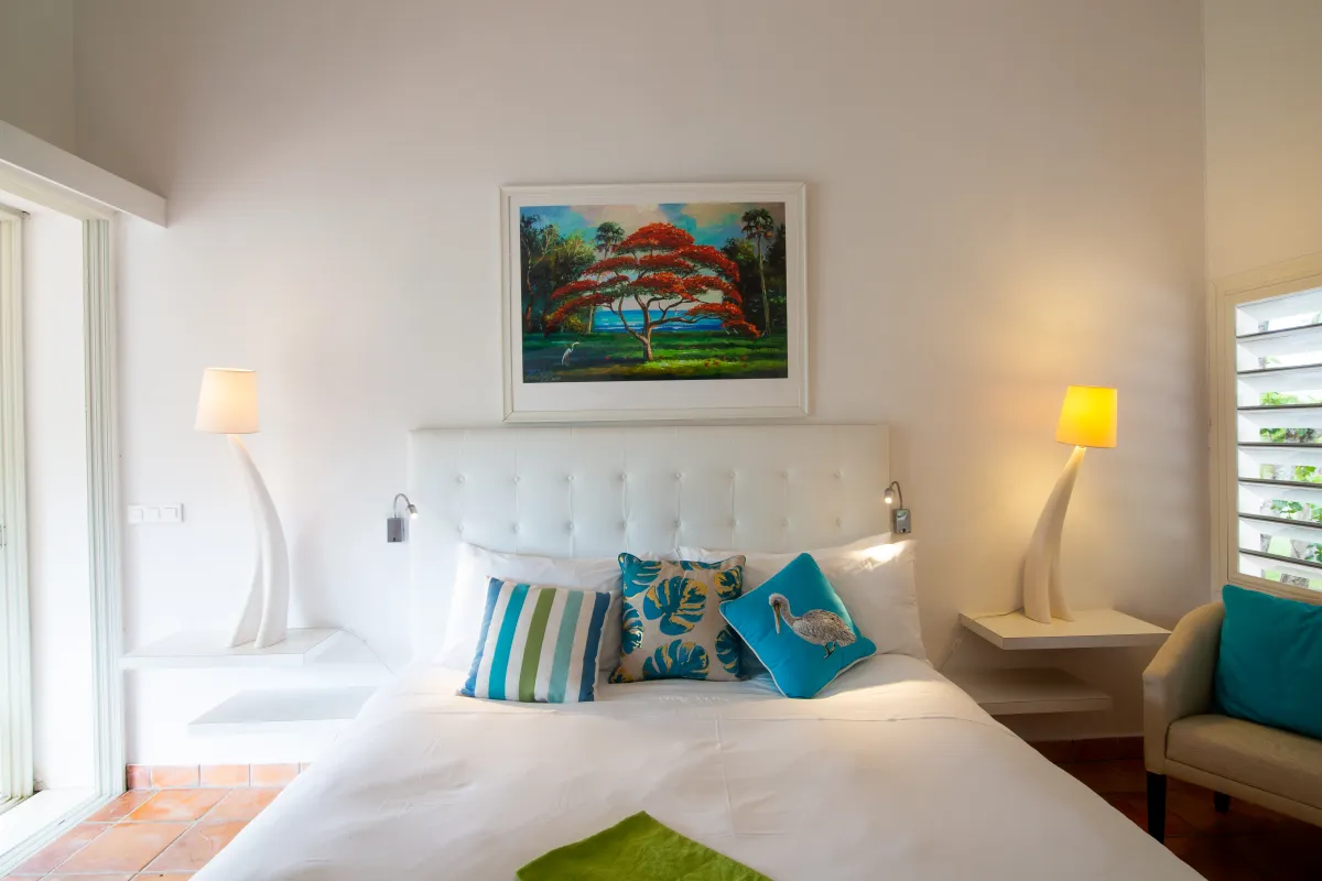 Villa Mes Amis: Bedroom with a white tufted headboard, colorful throw pillows, and modern bedside lamps