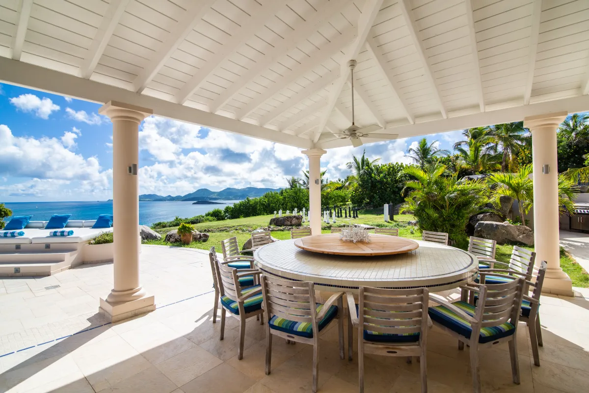Villa Mes Amis: Covered terrace with a large round dining table overlooking the ocean and tropical landscape
